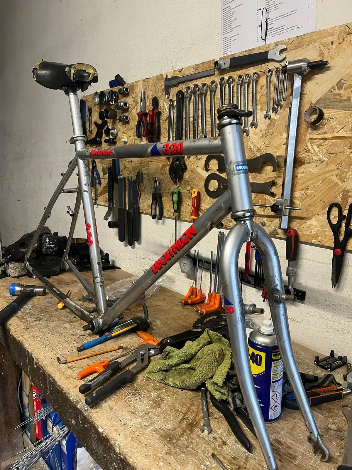 Un cadre et une fourche sur l'établi de l'atelier Ribine, outils au mur