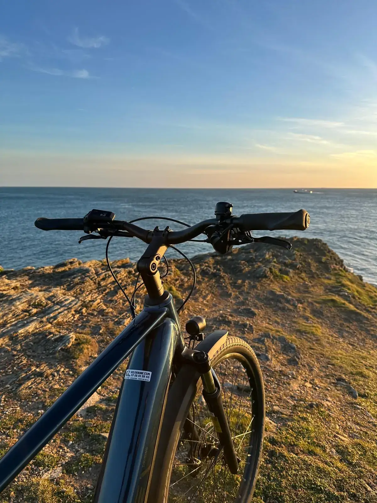 Vélo électrique posé face à la mer au coucher du soleil